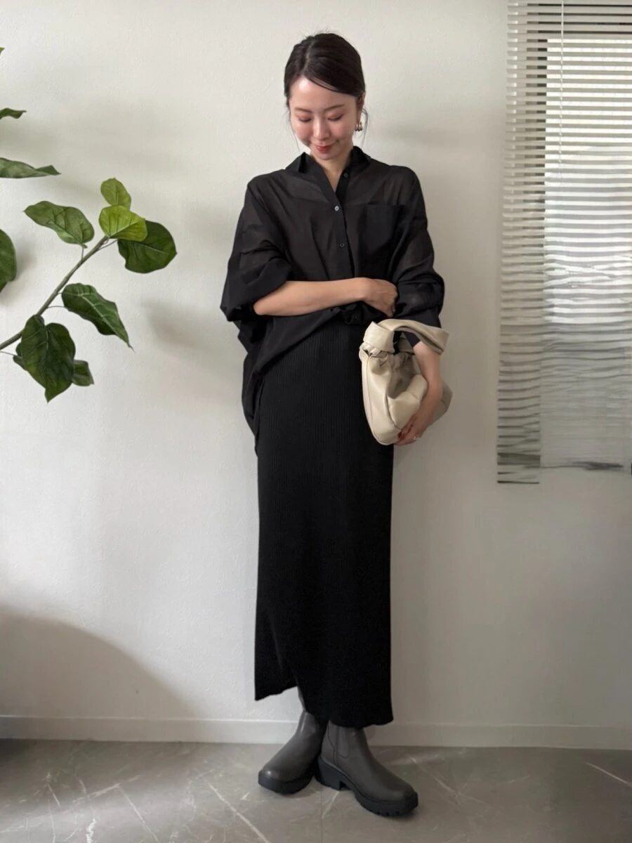 黒のシャツとロングスカートのワントーンコーデを着こなす女性