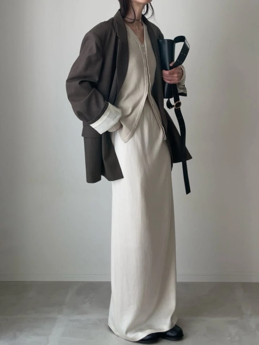 ブラウンのジャケットに白ロングスカートを合わせた女性の全身写真 ブラウンのジャケットに白ロングスカートを合わせた女性の全身写真