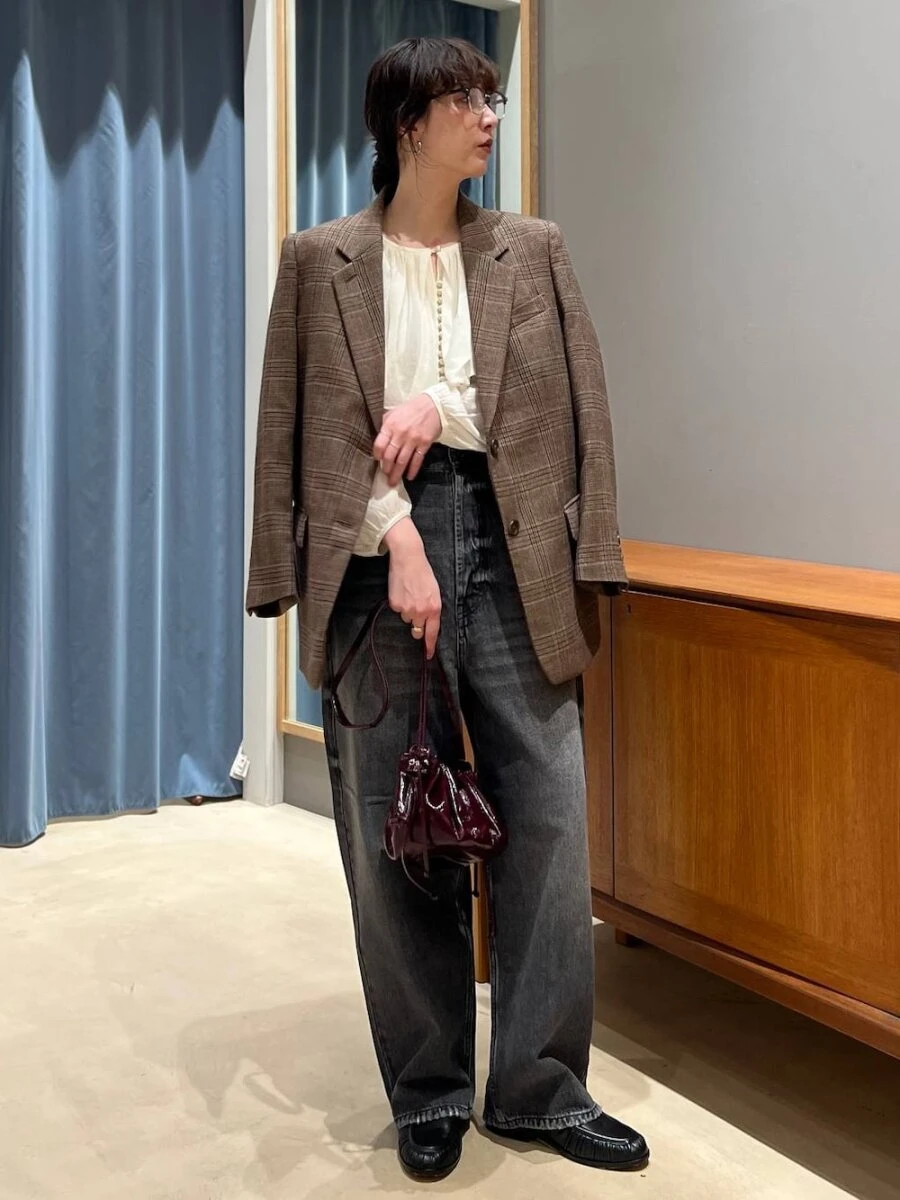 チェック柄ジャケットを肩掛けしデニムを持った女性の全身写真 チェック柄ジャケットを肩掛けしデニムを持った女性の全身写真
