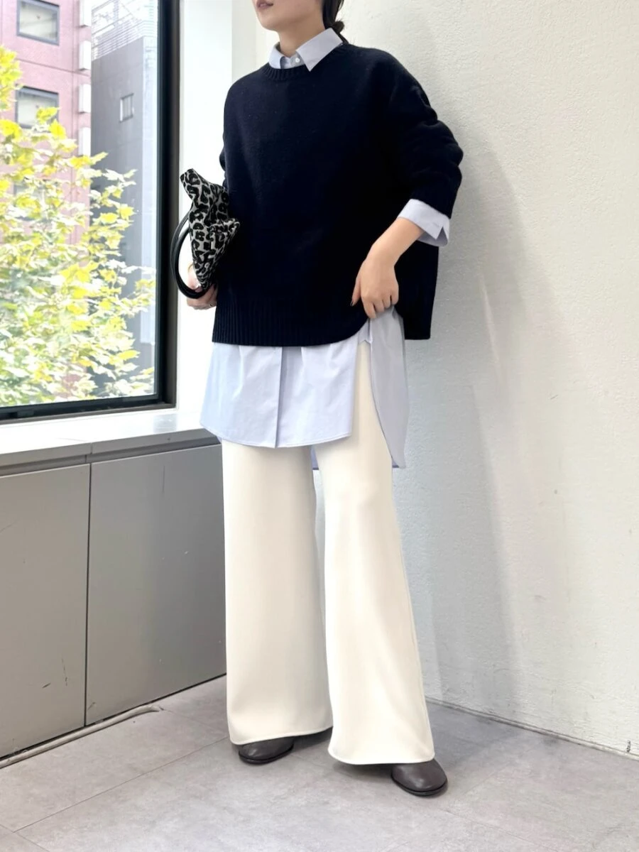 ブルーのシャツワンピースに黒ニットと白ワイドパンツを合わせる女性 ブルーのシャツワンピースに黒ニットと白ワイドパンツを合わせる女性