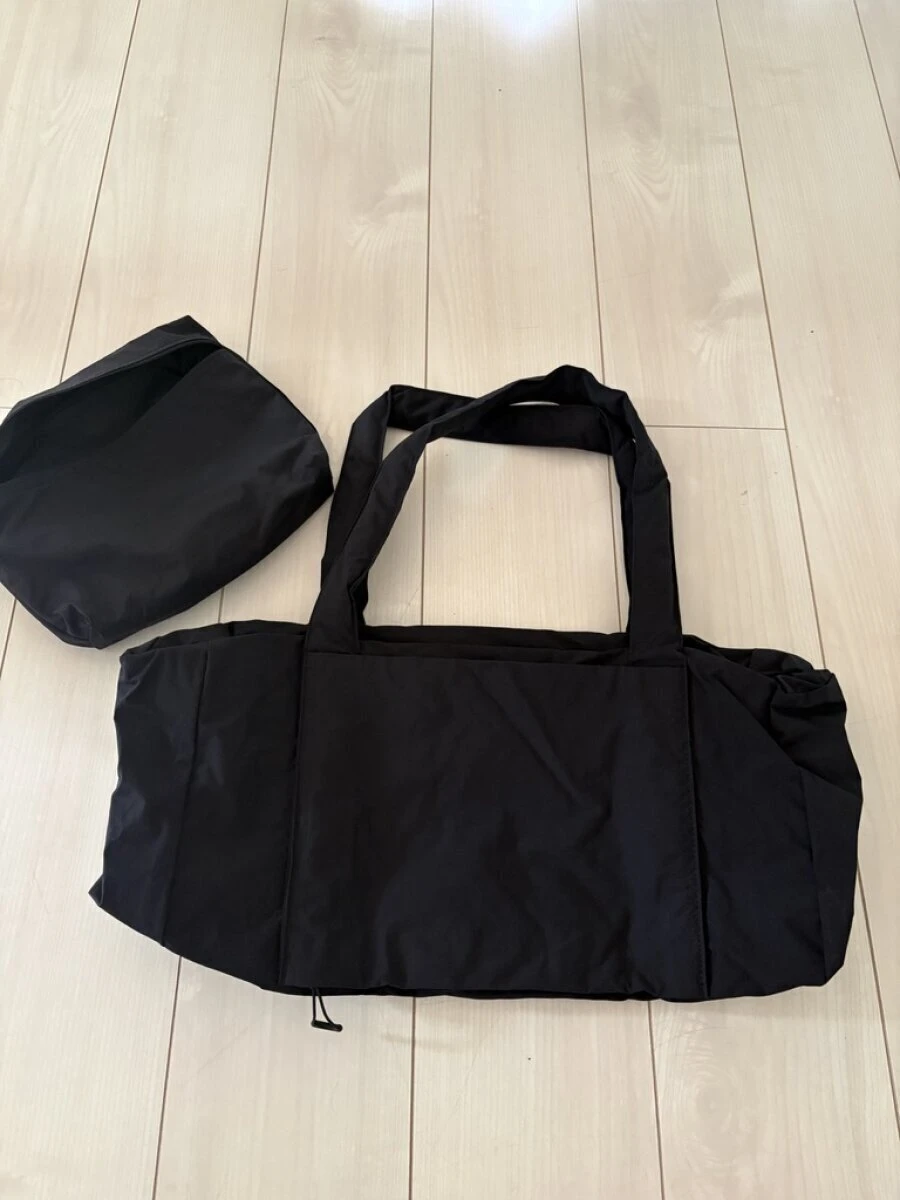 床の上に広げられた黒い再生ナイロンたためるボストンバッグと収納用のポーチ