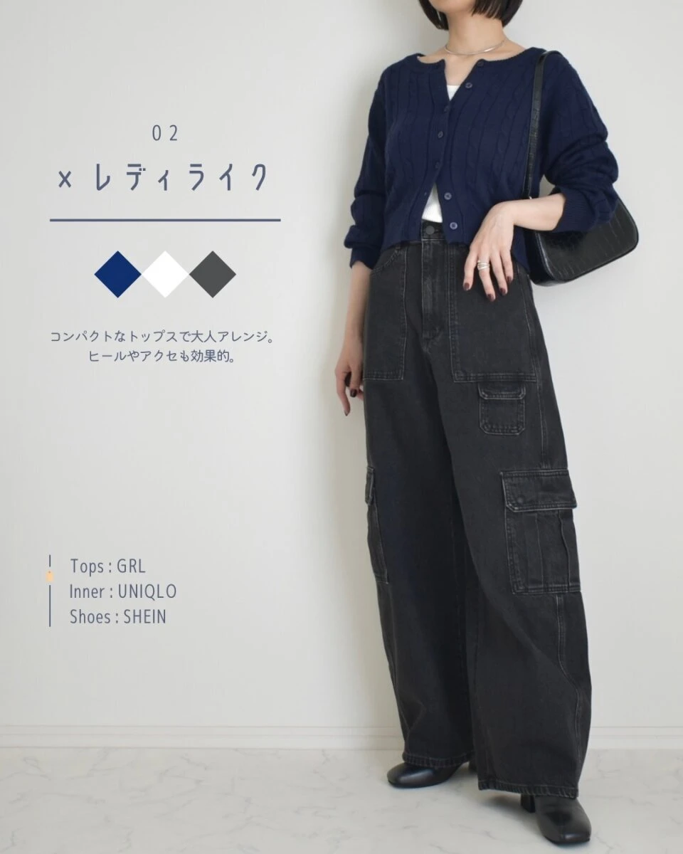黒いバレルユーティリティジーンズとネイビーのカーディガンを着用し、黒いハンドバッグを持つ女性の全身